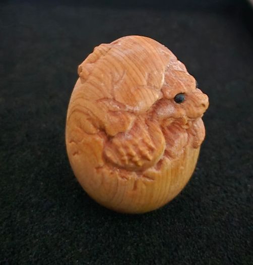 Carved wooden dragon hatching from an egg.