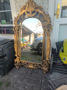 large, ornate gold mirror features a baroque frame