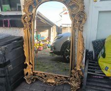 large, ornate gold mirror features a baroque frame