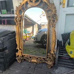 large, ornate gold mirror features a baroque frame