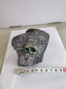Face rock with green eyes hand carved