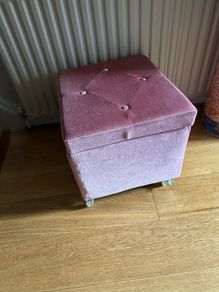 pink velour covered stool with interior storage space moves easily on castors