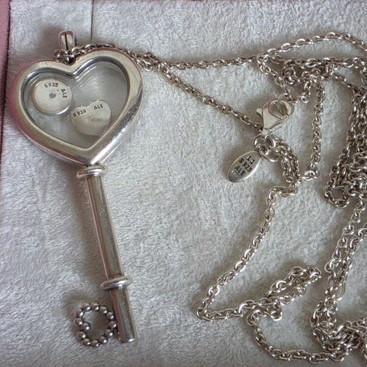 Pandora sterling silver key necklace with a heart,shaped floating locket and pink sparkling stones. Includes the two petite charms