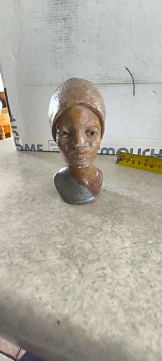 vintage image shows a handcrafted stone bust of a woman wearing a headscarf, often associated with Shona sculpture be carved from fruit serpentine stone from Zimbabwe