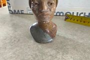 vintage image shows a handcrafted stone bust of a woman wearing a headscarf, often associated with Shona sculpture be carved from fruit serpentine stone from Zimbabwe