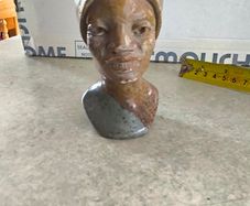 vintage image shows a handcrafted stone bust of a woman wearing a headscarf, often associated with Shona sculpture be carved from fruit serpentine stone from Zimbabwe