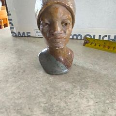 vintage image shows a handcrafted stone bust of a woman wearing a headscarf, often associated with Shona sculpture be carved from fruit serpentine stone from Zimbabwe