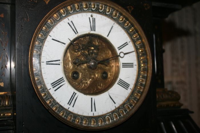 Victorian French Black Slate Mantle Clock (Very large and heavy) with bronze ornamentation Oversized. Open escarpment slate plate Roman numerals. Circa 1890s. Accented with Trojan head. Flanked by two Hellenistic ladies heads on sides. Rose cartouche mask