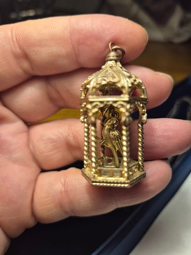 Vintage gilded bird cage with a bird pendant.