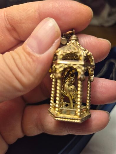 Vintage gilded bird cage with a bird pendant.