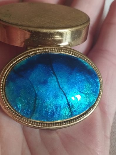 A vintage metal pill box with an enamel lid.