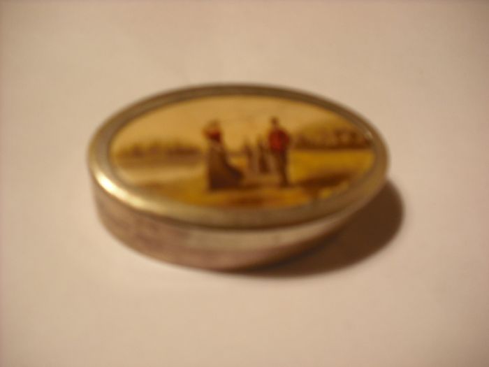 a antique pill box with golfer on it