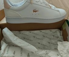 Brand new white Lacoste sneakers with blush pink suede heel detail and signature gold crocodile logo. Classic low-top design with white laces and chunky sole for everyday comfort. Never worn, in perfect condition, and comes with original box. Stylish, cle