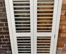 Vintage-style louvered white internal window shutter