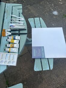 Paints, brushes, knives, and a canvas board
