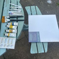 Paints, brushes, knives, and a canvas board