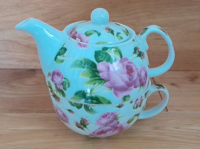 Tea for one: tea pot and cup with rose design on white