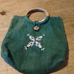 handmade boho style green burlap handbag featuring a circular wooden top handle and distinctive floral cowrie shell embellishments. Great condition