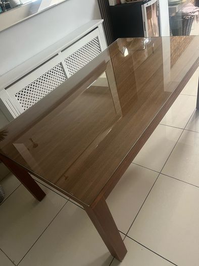 Brown wooden dining table with glass top