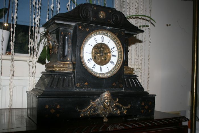 Victorian French Black Slate Mantle Clock (Very large and heavy) with bronze ornamentation Oversized. Open escarpment slate plate Roman numerals. Circa 1890s. Accented with Trojan head. Flanked by two Hellenistic ladies heads on sides. Rose cartouche mask