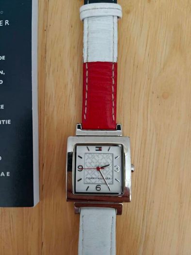 Tommy Hilfiger watch features a distinctive rectangular stainless steel case and a reversible red, white, and blue leather strap