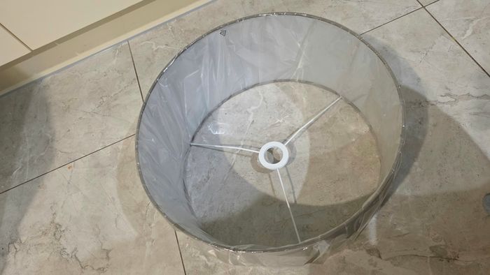 Brand new grey drum lampshade still sealed in its original plastic wrapping.