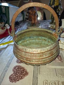 Antique Copper Cauldron features a Rustic Patina, a Swing Handle, and Distinctive Ribbed Detailing around the Rim. It resembles vintage metal pots often used for hearth decoration or as Planters. The piece shows significant oxidation and aging, characteri