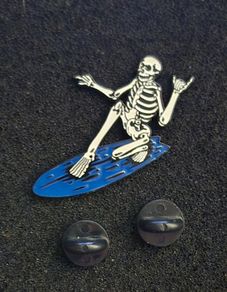 Surfing skeleton, pin back badge.