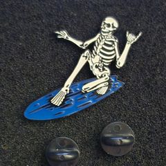 Surfing skeleton, pin back badge.
