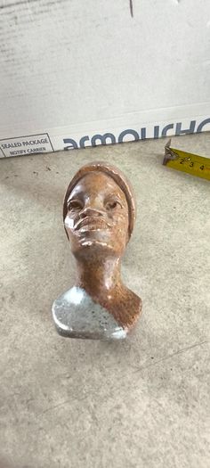 vintage image shows a handcrafted stone bust of a woman wearing a headscarf, often associated with Shona sculpture be carved from fruit serpentine stone from Zimbabwe
