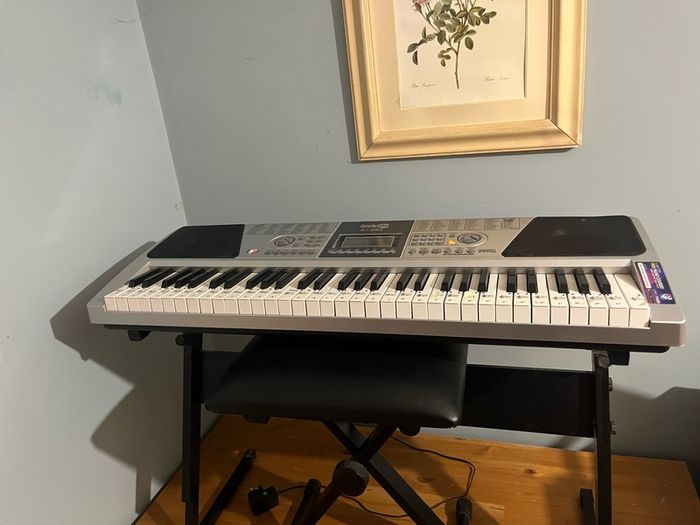 RockJam Electronic Keyboard Piano set up on a sturdy, matching heavy-duty Z-frame stand and an adjustable padded X-frame RockJam Keyboard Bench resting on a wooden surface.