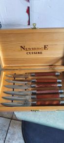 A Newbridge Cuisine set of six steak knives with serrated blades and wooden handles.