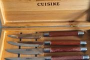 A Newbridge Cuisine set of six steak knives with serrated blades and wooden handles.