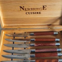 A Newbridge Cuisine set of six steak knives with serrated blades and wooden handles.
