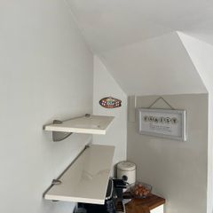 A pair of e floating wall shelves mounted on decorative metal shelf brackets.