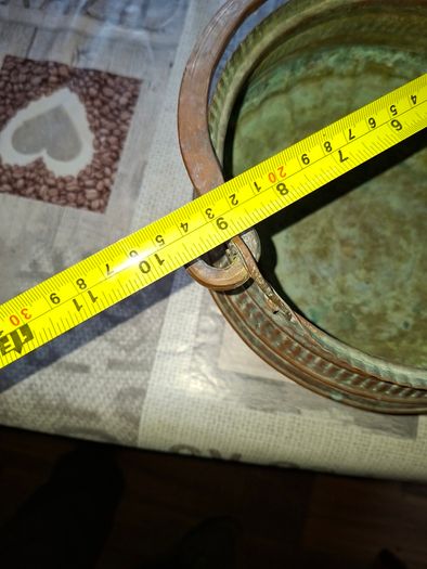 Antique Copper Cauldron features a Rustic Patina, a Swing Handle, and Distinctive Ribbed Detailing around the Rim. It resembles vintage metal pots often used for hearth decoration or as Planters. The piece shows significant oxidation and aging, characteri