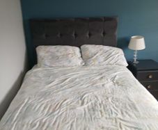 Double bed with grey upholstered headboard and storage drawer