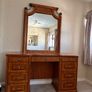 Crafted from stained hardwood with raised drawer panels, rounded pedestal edges, and an arched top mirror crown bordered by heavy metal or wood accent brackets. Nautical Rope Detailing: The upper accent panels on the mirror frame, the top left drawer, and Image 2