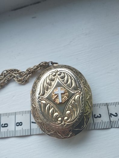A large medallion featuring religious symbols, suspended from a long chain.