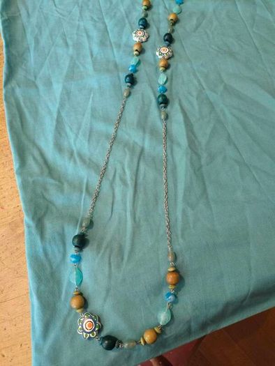 long, colorful beaded necklace featuring a mix of wood, blue, and white floral beads.