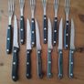 A 12-piece stainless steel steak knife and fork set with wooden riveted handles. Image 3