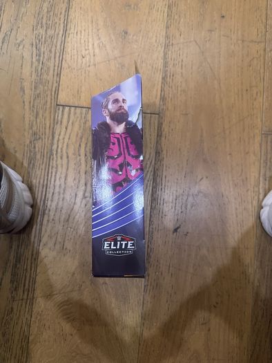 The item shown is the WWE Elite Collection Series 86 SummerSlam Seth Rollins action figure by Mattel, featuring his pink and black ring gear, TrueFX facial detailing, and themed accessories.