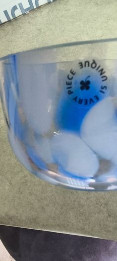 A hand-blown blue and white swirl art glass piece Small glass bowl with sticker say The phrase "EVERY PIECE IS UNIQUE" circles the clover.