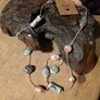 This handmade necklace features a combination of ceramic floral beads and silver-toned metal beads on a pink cord. Image 2