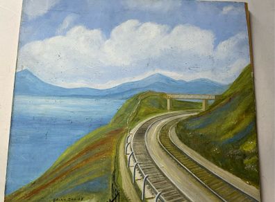 picture This piece depicts a railway line sweeping around a coastal bay beneath a footbridge and hillsides, signed Brian Davies in the lower left corner.