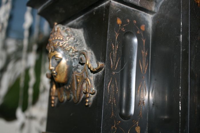 Victorian French Black Slate Mantle Clock (Very large and heavy) with bronze ornamentation Oversized. Open escarpment slate plate Roman numerals. Circa 1890s. Accented with Trojan head. Flanked by two Hellenistic ladies heads on sides. Rose cartouche mask