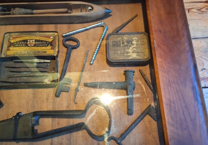 vintage shadow box containing a mix of antique tools, keys, and a loom.