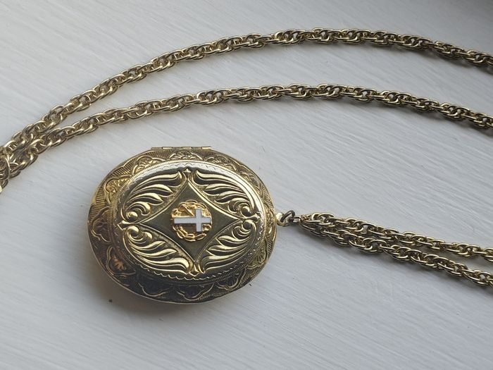 A large medallion featuring religious symbols, suspended from a long chain.