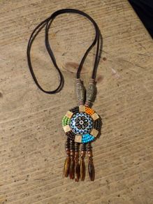 This is a bohemian-style long necklace featuring a resin pendant and beaded tassels.
