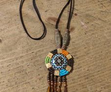 This is a bohemian-style long necklace featuring a resin pendant and beaded tassels.